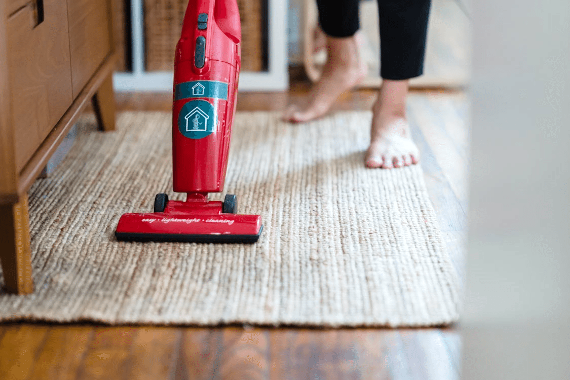 close-up of a person using a red vacuum on a carpet